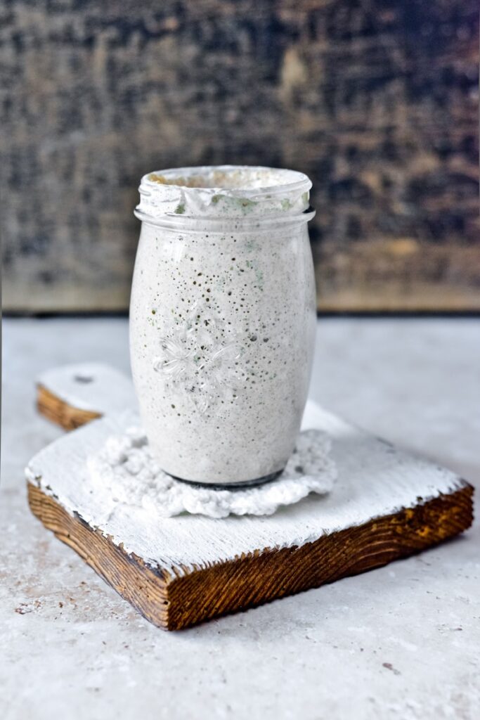 clear glass jar on white wooden table explaining What can I do with sourdough discard?