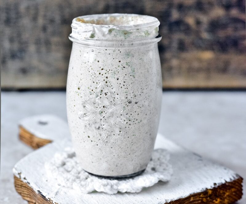 clear glass jar on white wooden table explaining What can I do with sourdough discard?